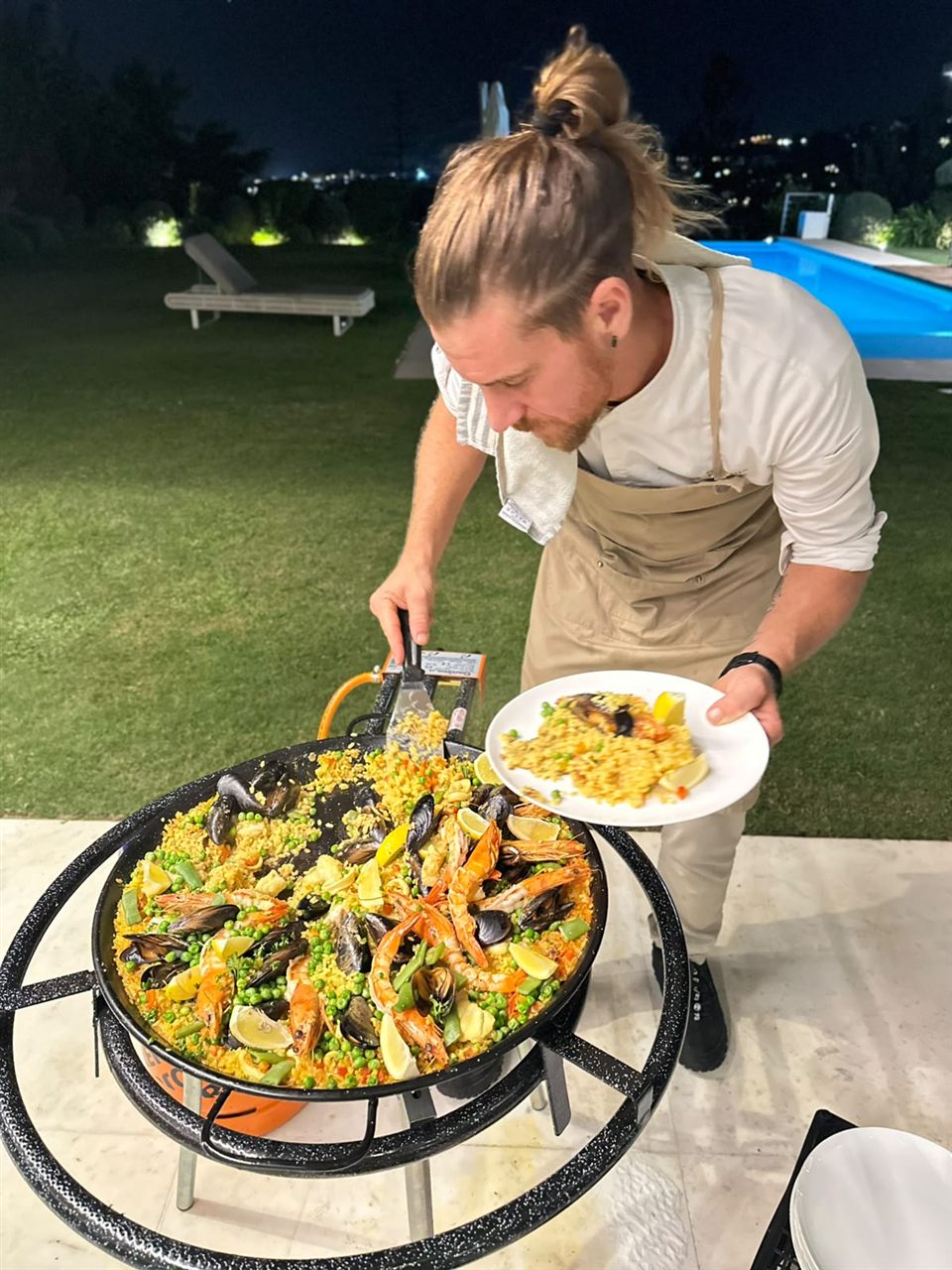 Christian Wybaux serving seafood paella in the garden at night