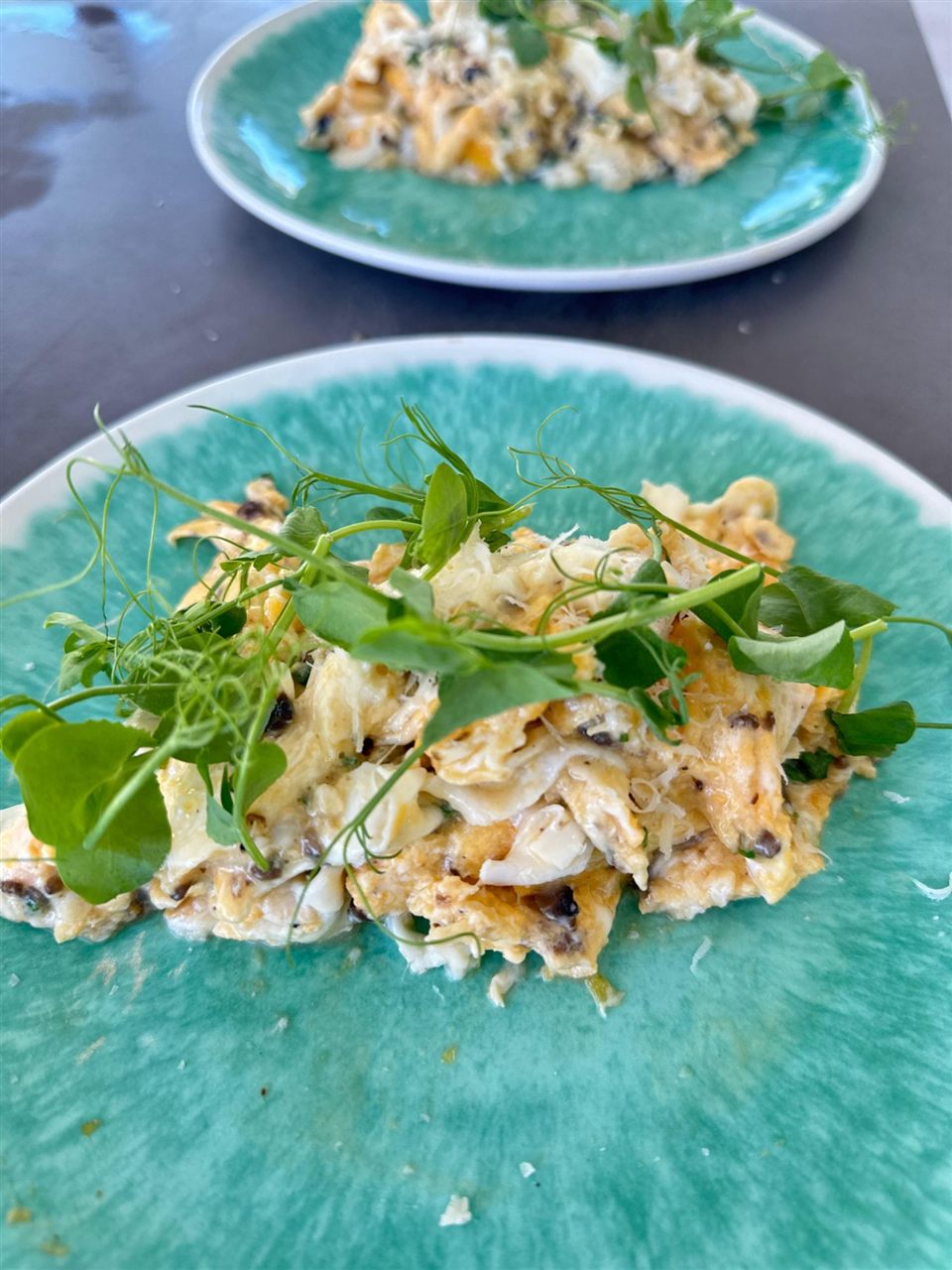 Truffle scrambled eggs with pea shoots on a turquoise plate